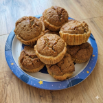 Egy halom frissen sült diós kosárka egy kék, sárga csillagokkal díszített papírtányéron, amelyet egy világos fából készült padlóra helyeztek.