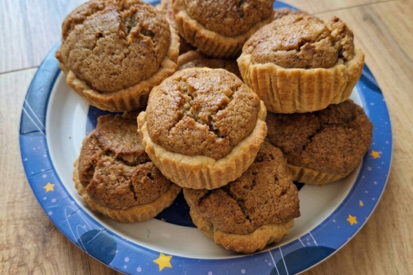 Egy halom frissen sült diós kosárka egy kék, sárga csillagokkal díszített papírtányéron, amelyet egy világos fából készült padlóra helyeztek.